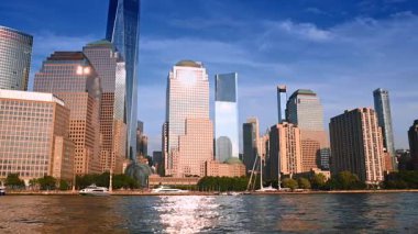 Parlak güneş New York 'un rıhtımındaki çarpıcı gökdelenleri aydınlatıyor. Metropolis 'in alçak açılı görüntüsü nehirden ufuk çizgisi.