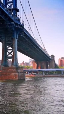 Tekneyle New York, ABD 'deki Manhattan Köprüsü' nün altından geçiyor. Metropolis 'te turizm. Dikey video.