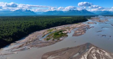 Sığ nehrin geniş deltasının üzerinden uçacağız. Nehrin etrafındaki çarpıcı dağlarla çevrili yeşil ormanlık vadi. Alaska 'da güneşli bir yaz günü.
