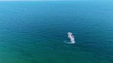 Güzel mavi su manzarasının yanından geçen bir jet ski motosikletini takip ediyorum. Yazın açık havada su sporu. Hava görünümü.