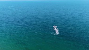 Güzel mavi su manzarasının yanından geçen bir jet ski motosikletini takip ediyorum. Yazın açık havada su sporu. Hava görünümü.