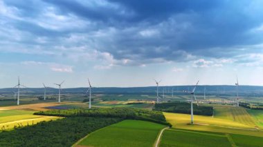 Modern rüzgar değirmenleriyle sürdürülebilir enerji üreten resimli alanlar. Gökyüzünü kaplayan kara bulutlar.