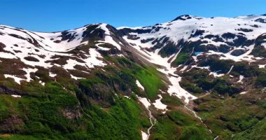 Dağın tepesinden biraz karla kaplı. Güneşli bir günde muhteşem kayaların üzerinde insansız hava aracı görüntüsü. Alaska doğası.