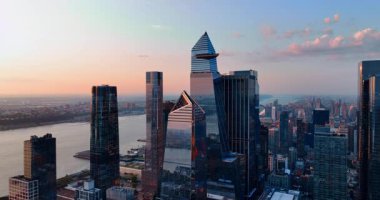 Manhattan şehir merkezindeki modern, şık gökdelenler. Gün batımında manzara üzerinde yükseliyor. Arka planda nehir manzarası. New York havası.