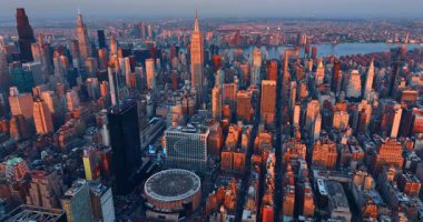 Batan güneş, ABD 'nin New York manzarasındaki yüksek binaların tepelerini aydınlatıyor. Gün batımında New York 'un engin manzarasına bakın..