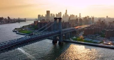 Doğu Nehri üzerindeki Williamsburg Köprüsü 'nün tepesine uçuyor. New York 'un puslu silueti gün batımında arka planda.