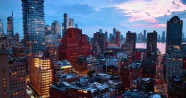 Şehir alacakaranlıkta ışıkları açıyor. İnsansız hava aracı görüntüleri New York, ABD 'deki çeşitli binaların üzerinde..