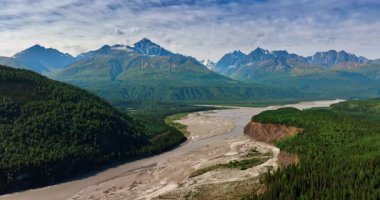 Göz kamaştırıcı Alaska manzaraları. Görkemli dağlar ve yemyeşil ormanlar Alaska 'da dolambaçlı bir nehri çevreleyen el değmemiş vahşi doğayı keşfetmek için mükemmel..