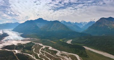 Alaska buzulu nehir manzarası. Alaska dağlık arazisinin göz kamaştırıcı manzarası. Bereketli vadilerde ve kayalık tepelerde kıvrılan bir buzul nehri..