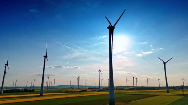 Türbinler yeşil enerji üretir. Geniş alanlar, gün boyunca açık bir gökyüzü altında rüzgar enerjisini kullanan rüzgar türbinleriyle benekli..