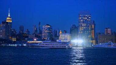 Modern çok katlı tekne nehir kıyısında hareket ediyor. New York 'un ışıklandırmalı güzel binaları.