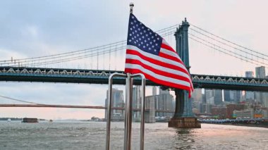 Metal raylarda dalgalanan Amerikan bayrağı. Manhattan Köprüsü ve New York silueti.