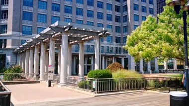 Bazı bitkilerle birlikte modern kentsel çevre. Obez beyaz adam esneyerek yürür. Jersey, ABD 'de güneşli bir gün.