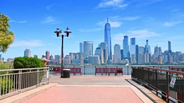 Güneşli Jersey 'de fenerlerle ve kırmızı banklarla güzel bir iskelede yürüyüş. Hudson nehri üzerinde Manhattan 'ın muhteşem manzarası.