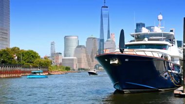 Nehir kıyısı boyunca çeşitli tekneler hareket ediyor. Manhattan 'ın yüksek binaları ve gökdelenleri.