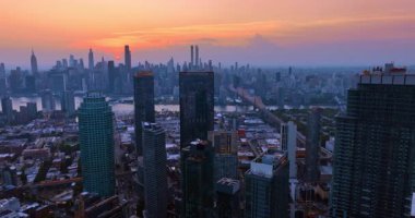 Günbatımında modern New York 'un yüksek binaların üzerinde uçmak. Doğu Nehri üzerindeki Queensboro Köprüsü 'ne yaklaşıyoruz. Metropolün üstündeki güzel turuncu gökyüzü..