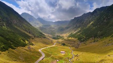 Vadinin üzerinden yükselen dağların arasından geçen otoyollar. Romanya 'da transfagarash otoyolu. Arkaplanda gri bulutlu bir manzara.