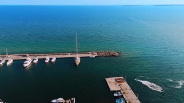 Sakin limandaki yelkenliler. Yelkenliler gün ışığında sakin suları ve açık gökyüzüyle sahil marinasında huzur içinde dinleniyorlar..