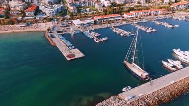 Gün batımında tekneleri olan bir marina manzarası. Güneş batarken tekneler güzel bir marinaya yanaşır ve canlı ve sakin bir atmosfer yaratırlar..