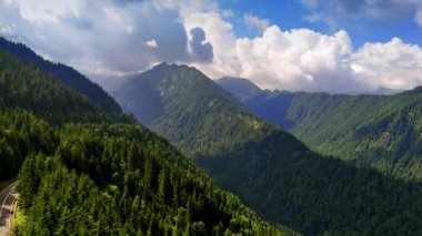 Bulutların altındaki manzaralı dağlar. Yeşil dağlar dramatik bulutların altında yükseliyor, doğanın güzelliğini serin bir noktada vurguluyor..