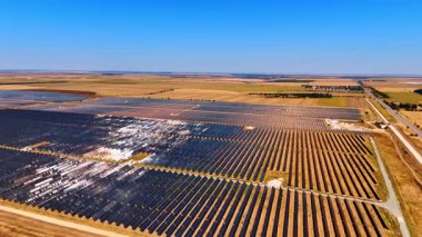 Güneş panelleri güneşli alanları örtüyor. Güneş panelleri açık mavi bir gökyüzünün altında hareket halindeki yenilenebilir enerjiyi vurguluyor..
