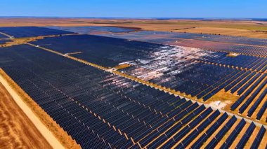 Enerji alanındaki güneş panelleri. Güneş panelleri, yenilenebilir enerji çözümlerine olan bağlılığını gösteren açık mavi gökyüzünün altında geniş bir alanı kaplıyor..