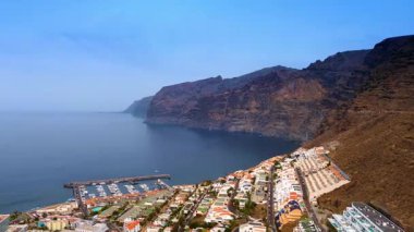 Çıplak kayanın yamacındaki yerleşim alanının üstünde uçuş. Atlantik Okyanusu kıyısındaki yat kulübüne yaklaşıyoruz. İspanya 'nın Tenerife Adası' na hava perspektifi.