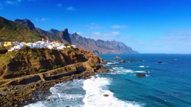 İspanya 'nın Kanarya Adaları, Tenerife' nin kayalık sahillerindeki Atlantik Okyanusu 'nun mavi suları üzerinde uçuş. Kıyıdaki kayalıklardaki sayısız villalara bakın..
