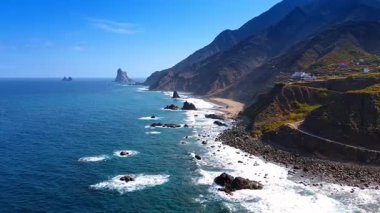 Atlantik Okyanusu 'nun dalgaları İspanya' nın Kanarya Adaları, Tenerife 'nin kayalık kıyılarına ulaşır. Adanın çıplak kayalıklarında bazı evler var..