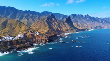Bir grup villa Atlantik Okyanusu 'nun kayalık kıyısında yer almaktadır. İspanya 'nın Kanarya Adaları, Tenerife' nin ulaşılamaz çıplak dağına bakın. Hava perspektifi.