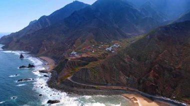 Dağ yamacı boyunca otoban yerleşim alanına çıkıyor. Atlantik Okyanusu kıyısındaki insansız hava aracı görüntüleri Tenerife, Kanarya Adaları, İspanya 'yı gösteriyor..