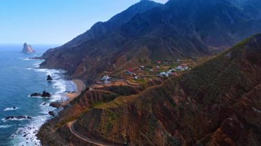 Atlantik Okyanusu kıyısında az bitki içeren nefes kesici dağlar. Yerleşim alanı kayalık sahilde yer almaktadır. Tenerife 'deki hava manzarası, Kanarya Adaları, İspanya.