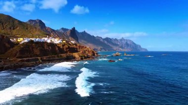 Beyaz köpüklü dalgalar İspanya 'nın Kanarya Adaları, Tenerife' nin kayalık sahillerine doğru yuvarlanıyor. Atlantik Okyanusu kıyısındaki kayalıklarda bulunan güzel beyaz villalar..