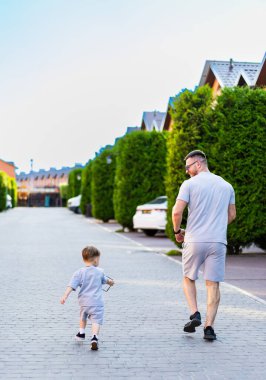 Baba ve oğul mahallede yürür. Bir baba ve küçük oğlu güneşli bir günde ağaçlarla kaplı sessiz bir mahallede birlikte dolaşırlar..
