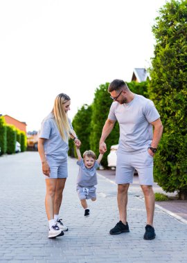 Aile birlikte dışarı çıkıyor. Çiftler ve küçük çocukları mutlu mesut ağaçlı bir caddede yürürler, güneşli bir günde neşeli anları paylaşırlar..