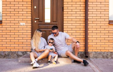 Aile merdivenlerde birlikte eğleniyor. Bir aile evinin merdivenlerinde oturur, çocuk bir aletle oynarken kaliteli zaman geçirir..