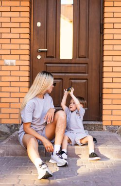 Anne ve çocuk dışarıda eğleniyor. Bir anne ve küçük çocuğu evlerinin merdivenlerinde oturmuş oyun oynarken keyifli bir anı paylaşıyorlar..