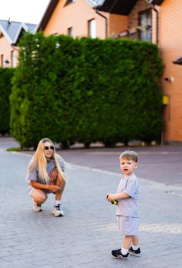 Sokakta oyuncak arabası olan bir çocuk. Güneşli bir günde annesi yakınlarda diz çökerken genç bir çocuk oyuncak bir araba tutuyor..