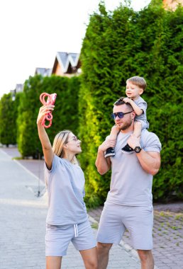 Aile yazın dışarıda eğlenmeyi sever. Mutlu bir aile parkta güneşli bir gezinti yapar. Birlikte güzel vakit geçirirken anılarını selfie ile yakalar..