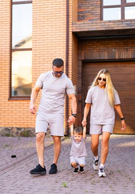 Aile dışarıda eğleniyor. Bir aile kaldırım taşı caddesinde neşeyle yürüyor, el ele tutuşuyor ve keyifli havanın tadını çıkarıyor..