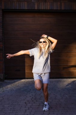 Garaj kapısının önünde neşeyle dans ediyor. Güneşli bir günde garajın dışında neşeyle dans eden bir insan tasasız bir hareket ve mutluluk sergiliyor..