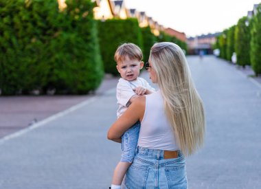 Banliyöde çocuklu bir anne. Bir anne küçük oğluyla güneşli bir banliyöde ağaçlarla kaplı sessiz bir sokakta yürür..