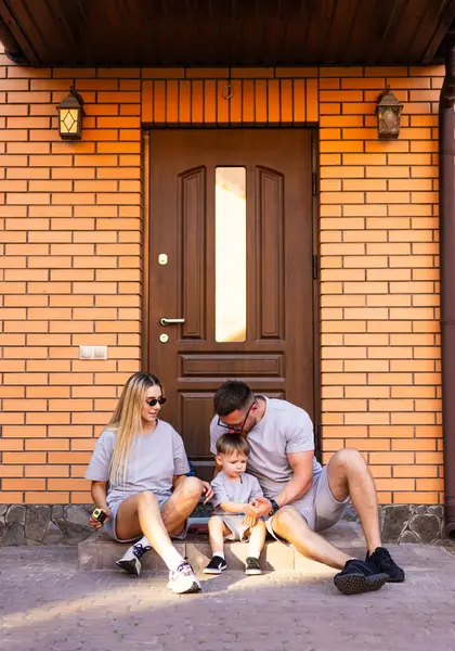 Aile, eşikte birlikte vakit geçirmekten hoşlanır. Üç kişilik bir aile, tuğla evlerinin kapısında rahatlar, neşeli anları ve kahkahaları paylaşır..