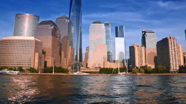 Parlak güneş New York ufuk çizgisindeki çarpıcı binaların cephelerini aydınlatıyor. Gündüz vakti Doğu Nehri 'nde tekne turu.