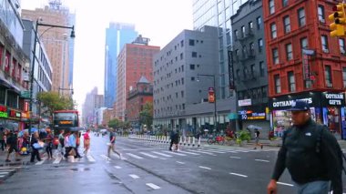 Yayalar yağmurlu bir günde New York 'ta karşıdan karşıya geçerler. Metropolis 'in yüksek binalarının alçak açılı görüntüsü.