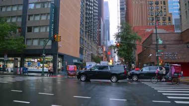 Yağmurlu bir günde New York caddesinde yürümek. Otomobiller, otobüsler ve tribünler yol kenarında.