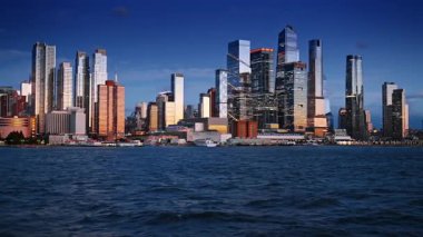 Batan güneş, Doğu Nehri 'nin rıhtımındaki binaları aydınlatıyor. New York silueti, ABD nehirden gün batımında.