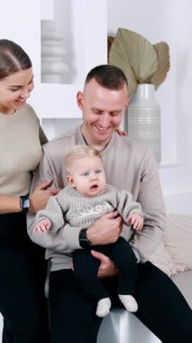 Kanepe korkuluklarında oturan gülümseyen adam. Kadın kocasına yakın duruyor. Mutlu aile fotoğrafı. Dikey video