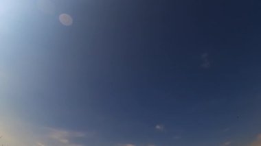 Mavi gökyüzünde küçük ışık bulutları beliriyor. Yazın alçak açılı gökyüzü manzarası. Zaman Uygulaması.