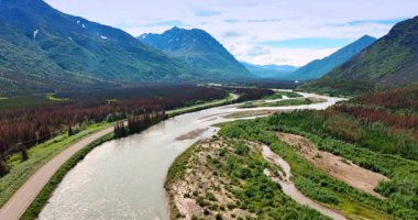 Vadideki kayaların arasında akan nehrin üzerinden uçmak. Manzarayı saran puslu dağlar. Alaska, ABD.